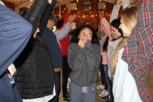 Individual smiling gleefully covering face as he or she passes through a group of individuals with their arms in the air